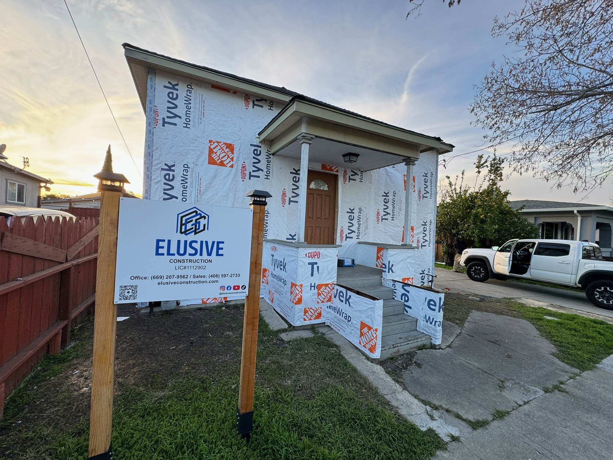 Home under construction wrapped in weather barrier with the Elusive Construction site sign, San Jose